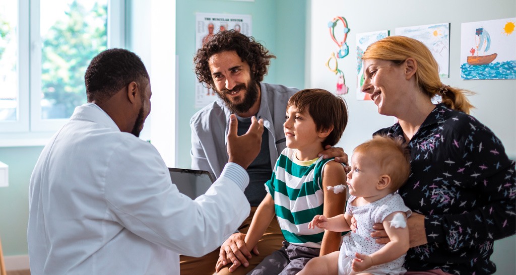A pediatrician speaks with a family with two young children