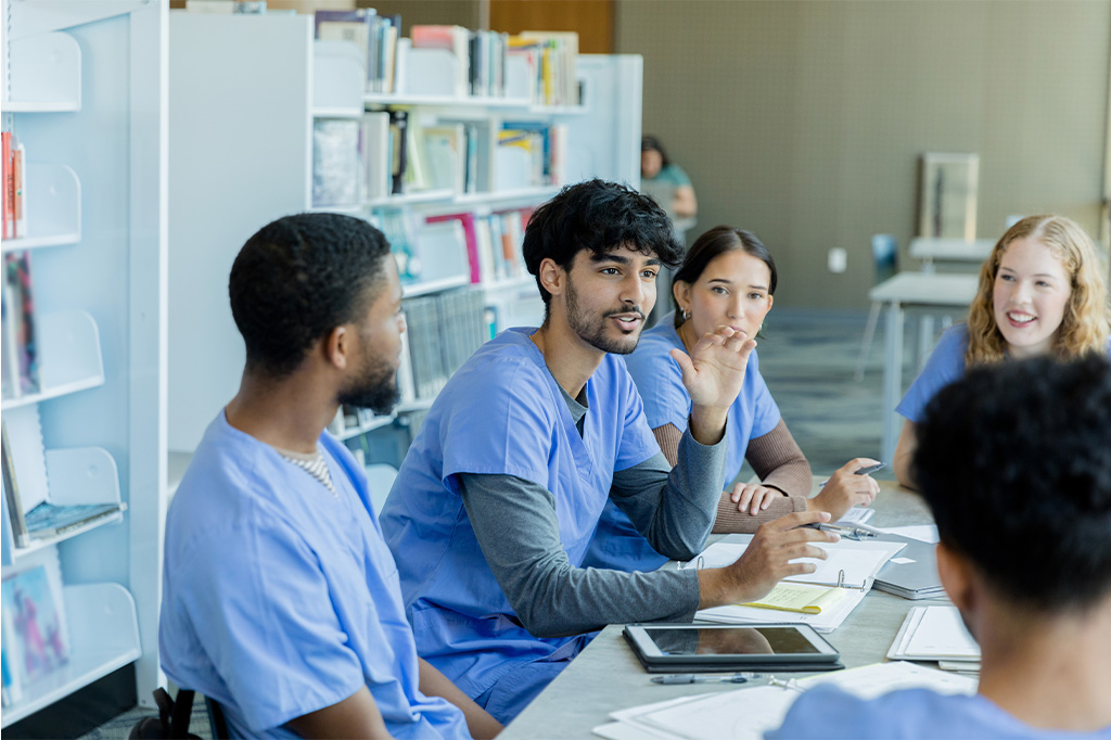 A group of medical professionals in scrubs participate in a group discussion