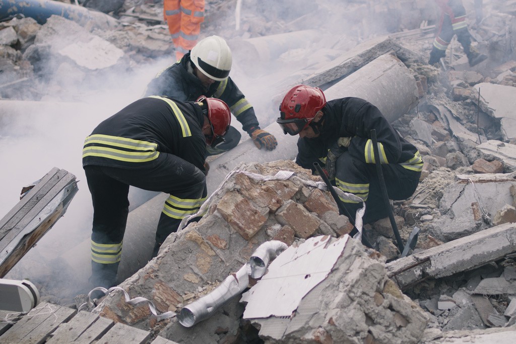 Three emergency firefighters working in the rubble of a collapsed building.